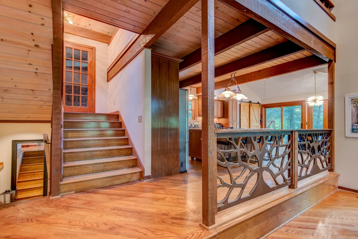 An open area combining a wooden staircase, decorative railing, and a kitchen space, all bathed in natural light from generous windows. The layout encourages family gatherings, meal preparation, and celebrations tied to seasonal festivals or local events.