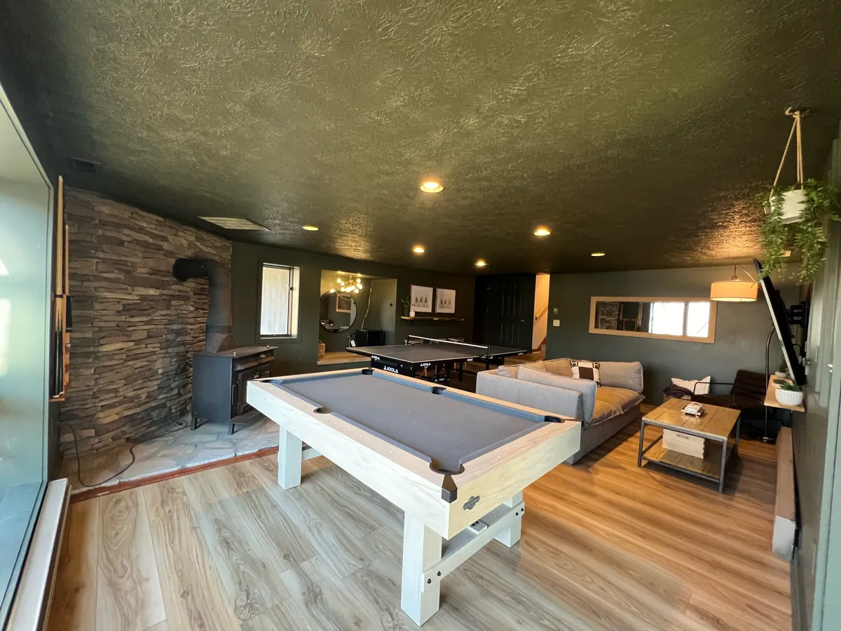 A friendly, relaxed entertainment area centered around a pool table, complemented by a sofa, stone wall accents, and stylish lighting. The space is ideal for tournaments or casual hangouts, emphasizing camaraderie and celebration.