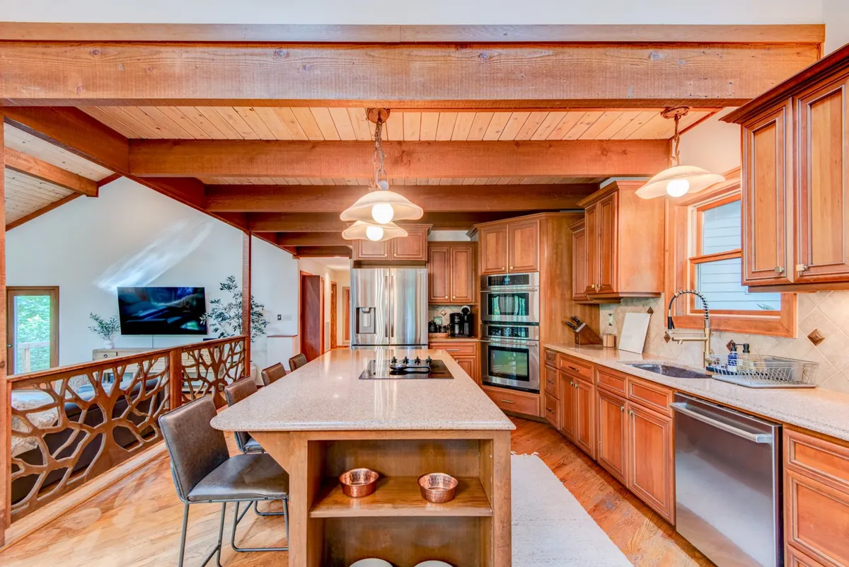 A view of the kitchen's central island surrounded by cabinets and stainless steel appliances, this scene invites guests to cook together or enjoy casual meals. The lighting and layout create a warm, functional hub for group gatherings and shared culinary adventures.