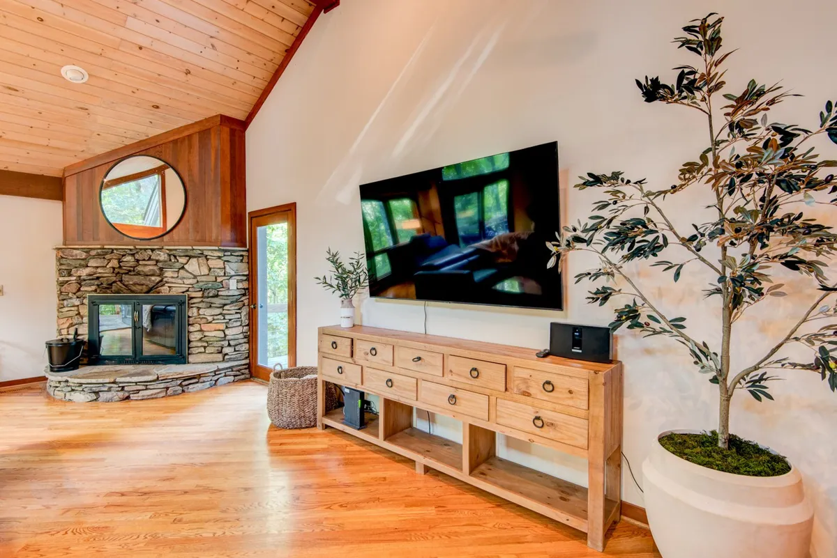 A welcoming living area centered around a striking stone fireplace, with a large television and wooden accents. The setting is perfect for warming up after wintertime mountain excursions, or for gathering with family and friends on chilly evenings.